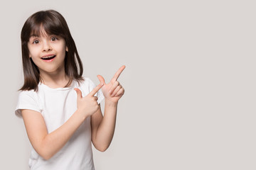 Little girl pointing fingers to the side copy space background