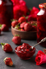 Strawberry jam in a can and fresh strawberries on a dark background, summer harvest