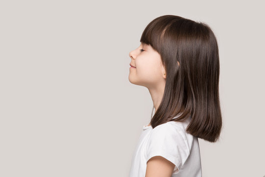 Profile of serene little girl isolated on grey studio background
