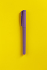 Purple pen on yellow paper background. Central composition. Back to school, education concept. Top view. Flat lay.
