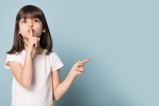 Funny little girl hold finger on lips pointing on copyspace