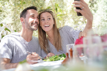 Happy couple taking sefie during outdoor lunch