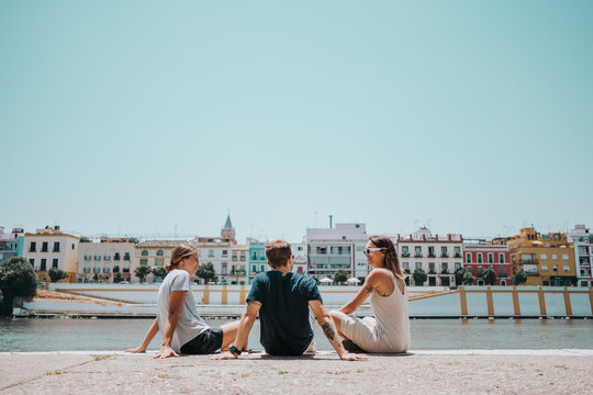 Three friends sitting in the sun on the bank of a river