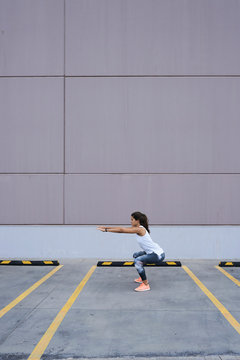 Sportswoman warm up exercises with body. Squats.