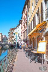 Old narrow street in Annecy, France. Medieval bright buildings in sunny summer day. 