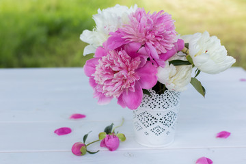 Obraz na płótnie Canvas Beautiful soft pink peonies in vase on white wooden background outdoors. Summer flowers in blossom. Nature, fresh pink flowers concept