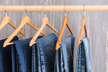 Clothes rack with stylish jeans pants near grunge wall - obrazy, fototapety, plakaty