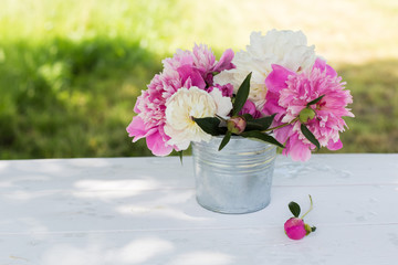 Beautiful soft pink peonies in vase on white wooden background outdoors. Summer flowers in blossom. Nature, fresh pink flowers concept