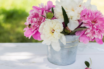 Beautiful soft pink peonies in vase on white wooden background outdoors. Summer flowers in blossom. Nature, fresh pink flowers concept