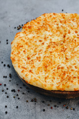 Sliced pie with cheese on a wooden board on grey background. Khachapuri