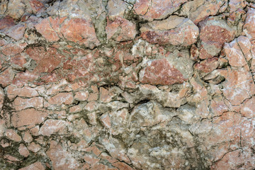 Wall texture of old damaged red stone close-up