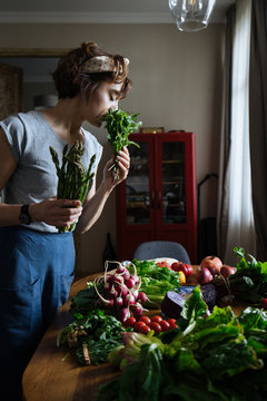 Woman in kitchen with fresh vegetables on table