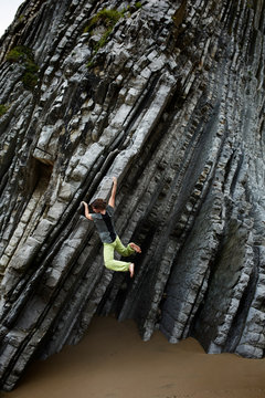 Female climber  bouldering on beach cliffs of natural grooves or flysch