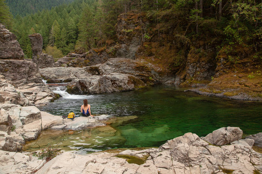 Active woman relaxing beside a natural pool in the forest.