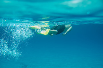 Full length male diver swimming underwater with fins.