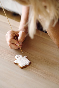 Crop woman making ghost cookie