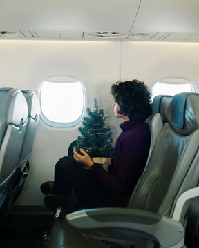 Woman with Christmas tree looking at the window of the airplane