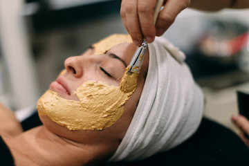 Woman applying gold mask at spa center