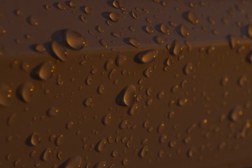 Raindrops or dew on a white plastic surface at sunset