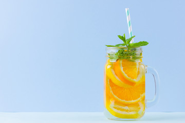 Infused water with fruits on blue background. Mug delicious refreshing drink of mix fruits with mint on blue background. Iced summer drink in mason jar. Minimalism