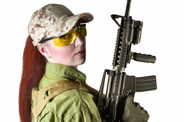 Portrait of young and beautiful military soldier woman with red hair holding an automatic rifle...