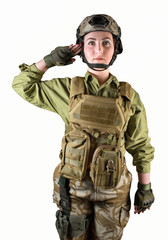 Young beautiful fully equipped military soldier woman in protective armor tactical vest, helmet, camouflage pants,holster and gloves standing and saluting, isolated photo.