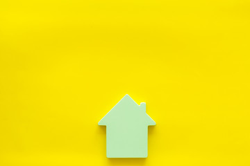 Fototapeta na wymiar Search for a new house concept with house figure on yellow office desk background top view space for text