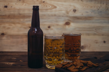 two beer mugs and a beer bottle on a wooden background
