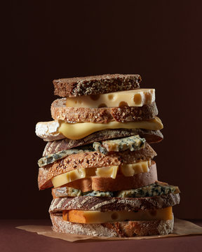A stack of bread and cheese on parchment paper around a dark bac