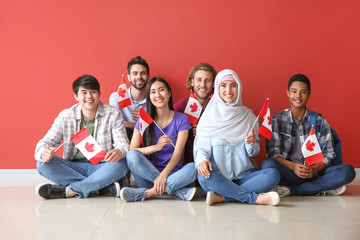 Groupe d& 39 étudiants avec des drapeaux canadiens assis près d& 39 un mur de couleur