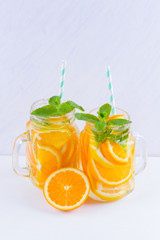 Infused water with fruits on white background. Mug delicious refreshing drink of mix fruits with mint on white background. Iced summer drink in mason jar. Minimalism