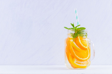 Infused water with fruits on white background. Mug delicious refreshing drink of mix fruits with mint on white background. Iced summer drink in mason jar. Minimalism