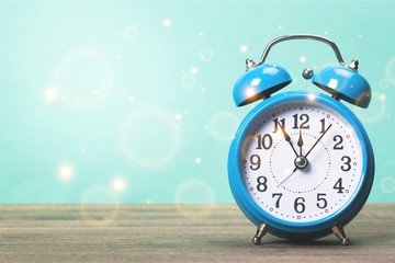 Blue retro alarm clock on wooden table on pastel background