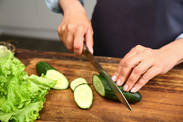 Mature woman cutting vegetables in kitchen, closeup