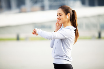 Sports woman doing exercises and listening to music in the urban environment
