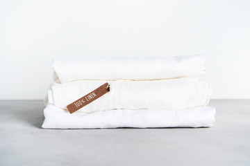 Stack of organic flax with tag of 100% linen on light background with space for text.