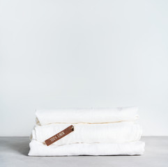 Stack of organic flax with tag of 100% linen on light background with space for text.