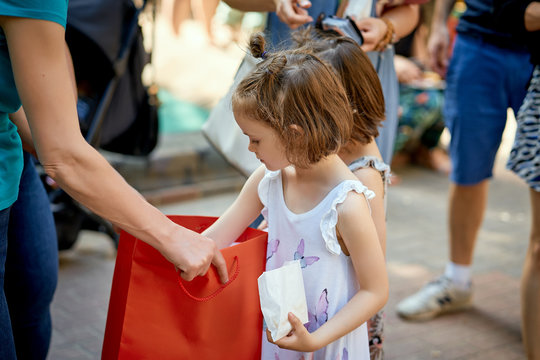 Pretty Little Girl Takes Out Lottery Ticket At Family Picnic On Summer's Day