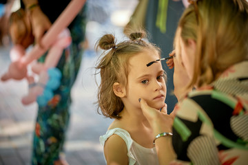 Portrait of little girl while painting face on children's picnic