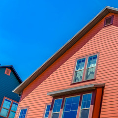 Square Exterior of home with a combination of red wood section and neutral wall