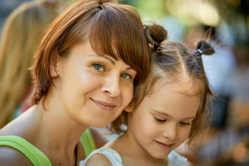 Portrait of mother and lovely little daughter at family picnic on summer day.