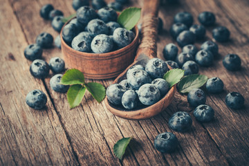Blueberries in wooden spoon on old wood background. Healthy eating and nutrition concept.