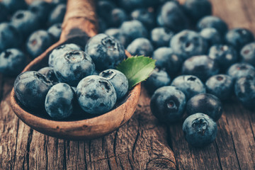 Blueberries in wooden spoon on old wood background. Healthy eating and nutrition concept.