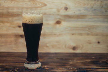 glass of dark beer on a wooden background