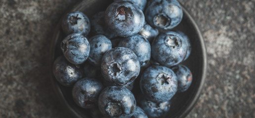 Freshly picked blueberries in  bowl on old metal background. Healthy eating and nutrition.