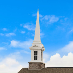 Square frame White steeple on top of the pitched roof of a church with brick exterior wall