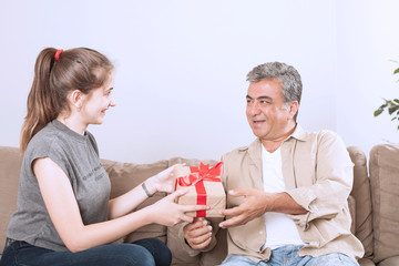 beautiful girl giving a gift box to her father