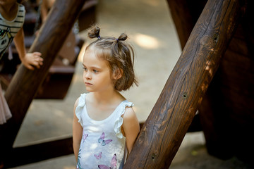Little girl stands alone on the playground with pensive face