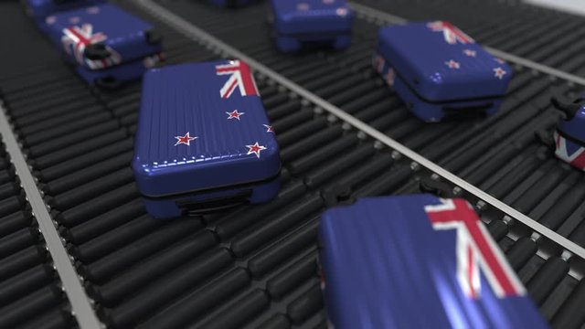 Many travel suitcases featuring flag of New Zealand on roller conveyer. Tourism related conceptual animation