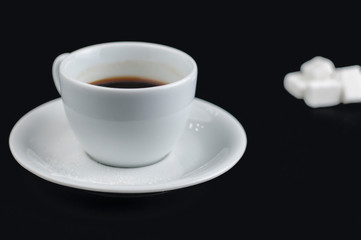 White coffee cup with sugar cubes isolated on a black background